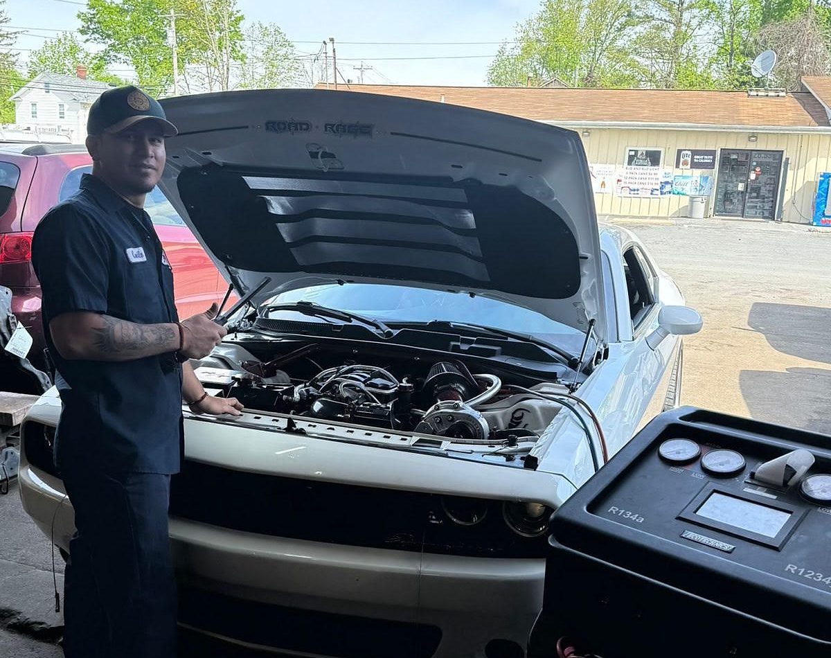 A technician checking under the hood outside the shop